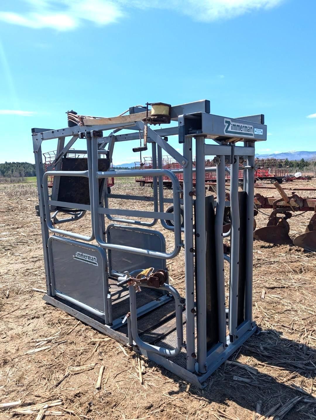 Metal livestock chute in a dirt field under a blue sky