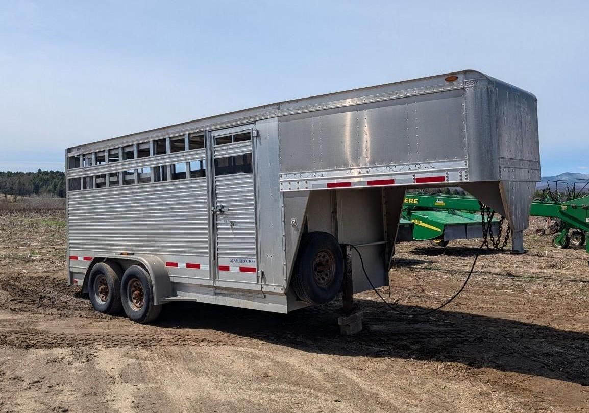 Silver livestock trailer on a dirt lot.