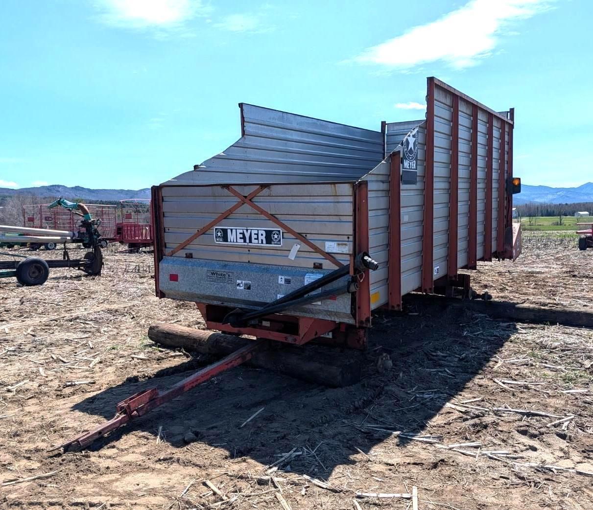 Trailer with metal siding in an open field under a blue sky.