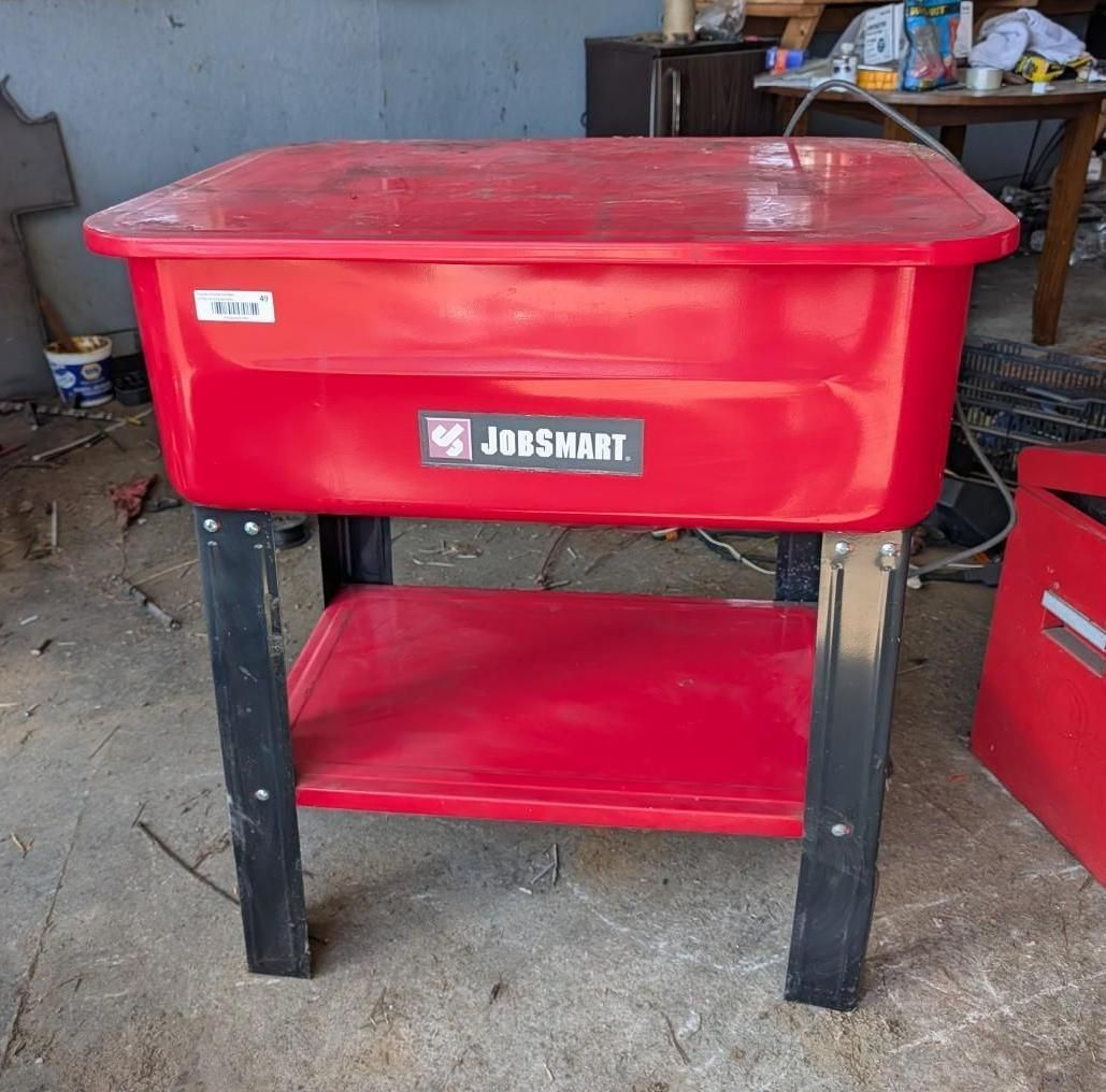 Red JobSmart utility cart with black legs on a concrete floor in a workshop/garage.