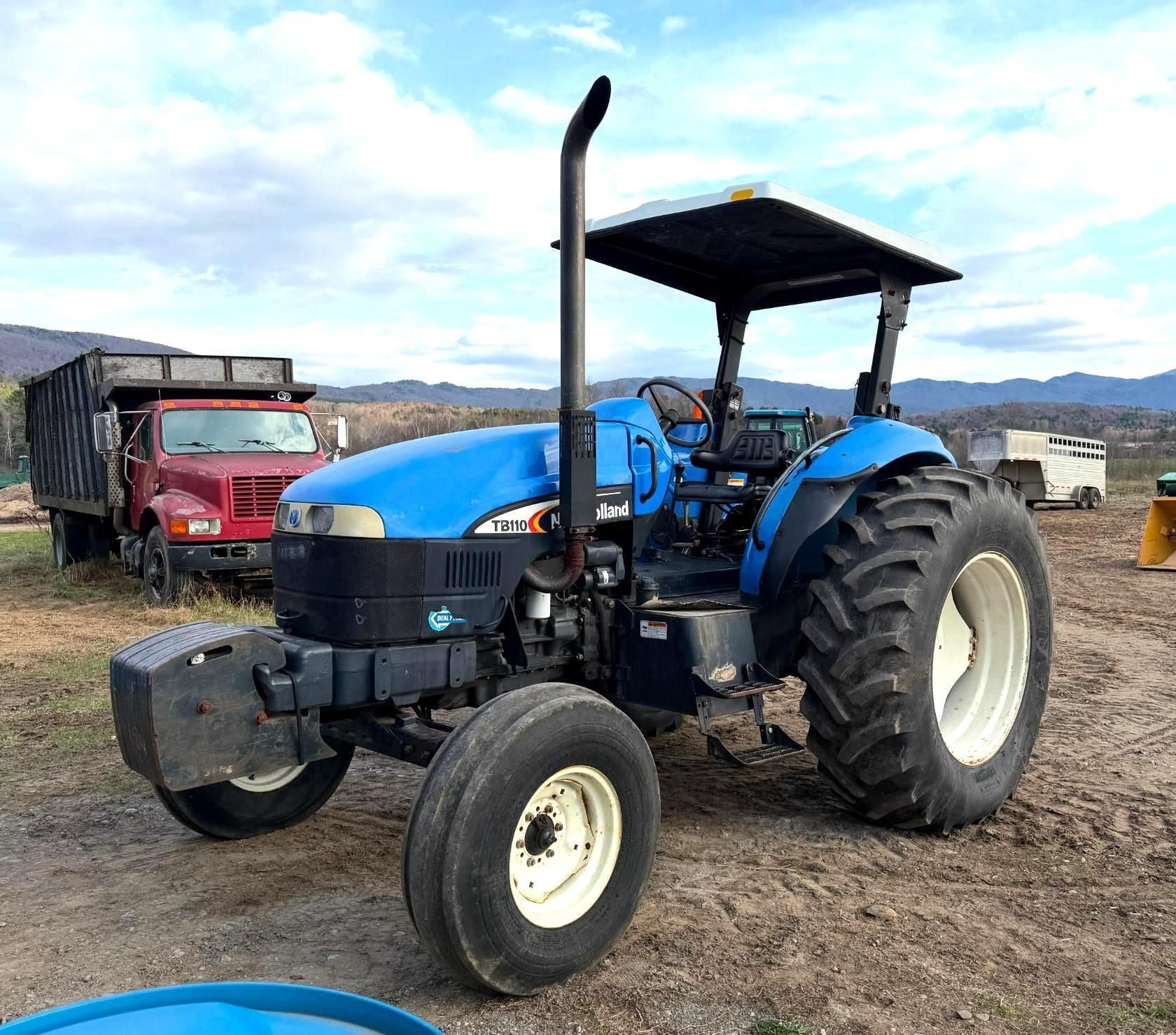 Blue tractor with canopy parked on a farm field.