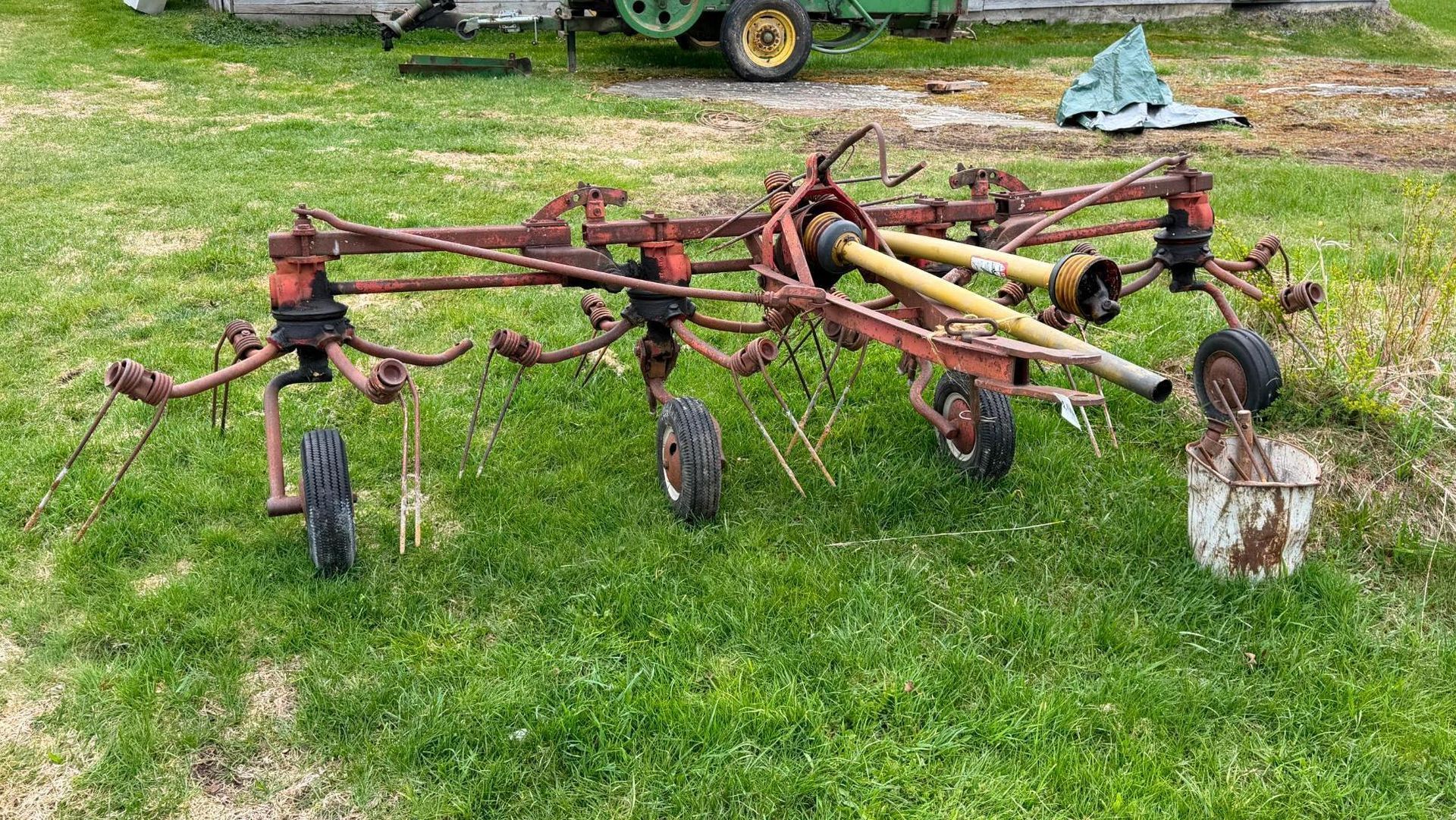 Agricultural implement with wheels and tines sitting on grass outdoors