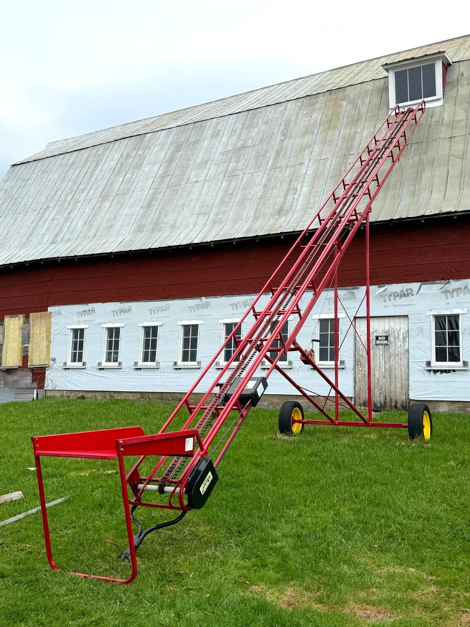 Long red ladder reaches a small attic window on a red-and-white barn roof