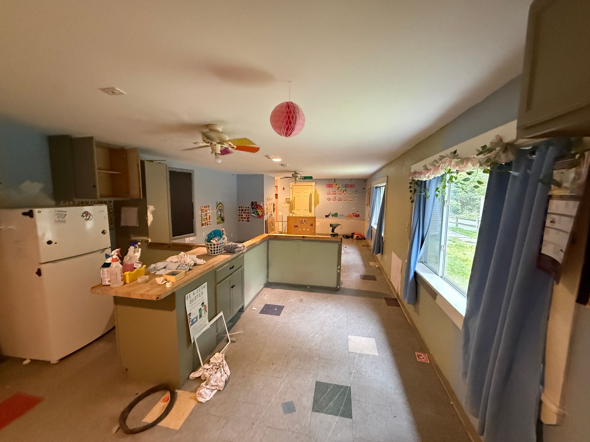 Spacious kitchen with green cabinets, white fridge, large window