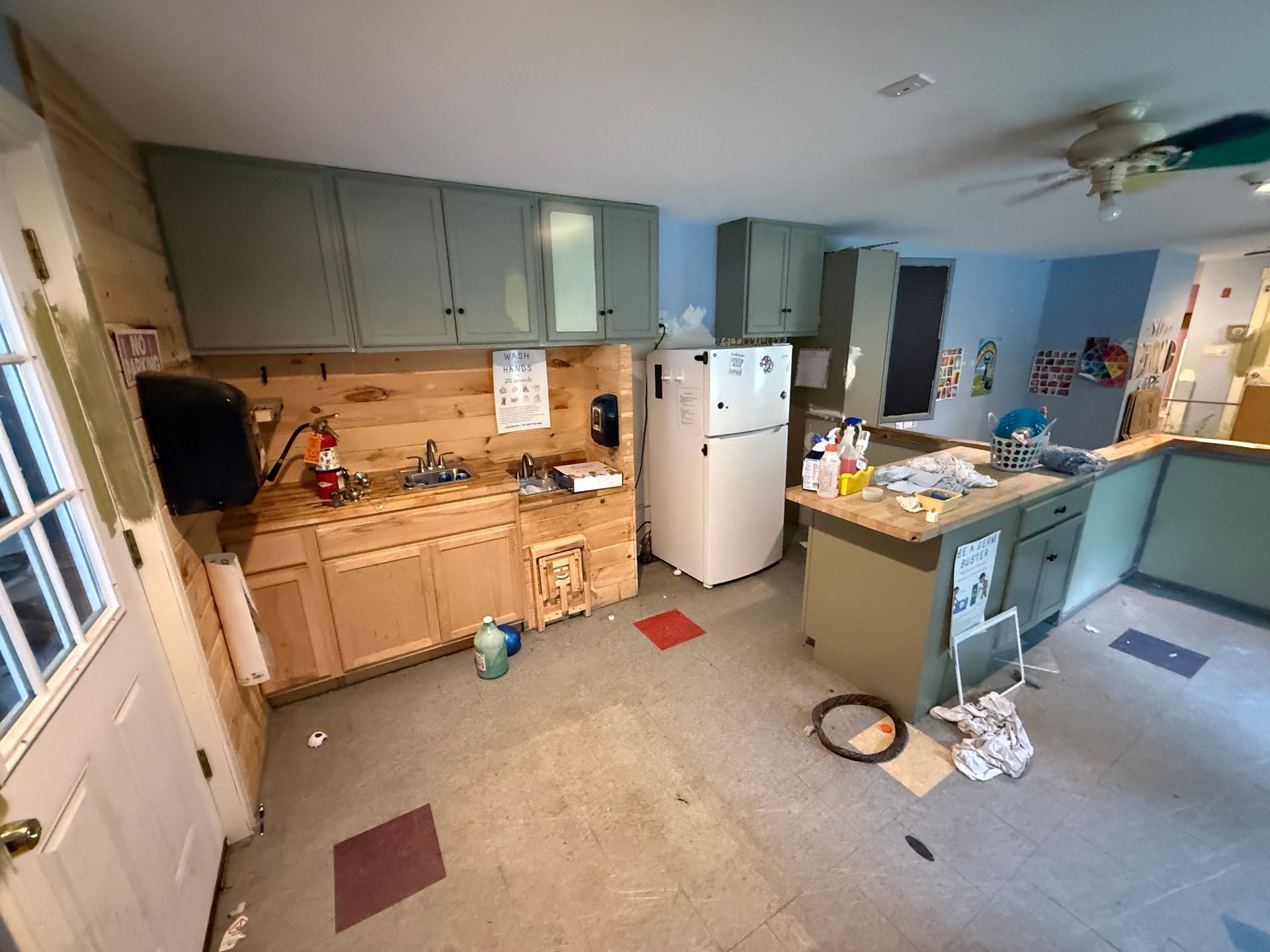 Messy kitchen with blue walls, wood cabinets, white fridge