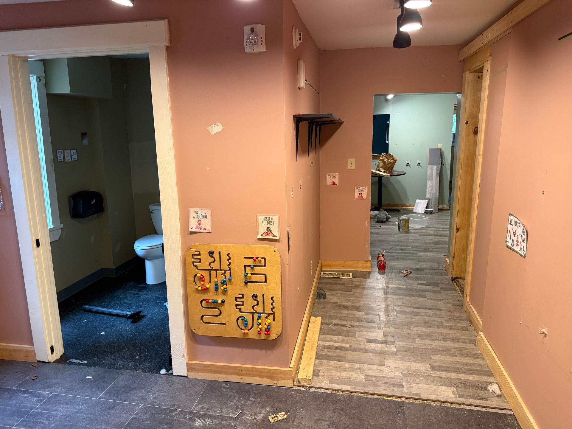 Renovated hallway with pink walls, wood flooring, and open doorways in a home