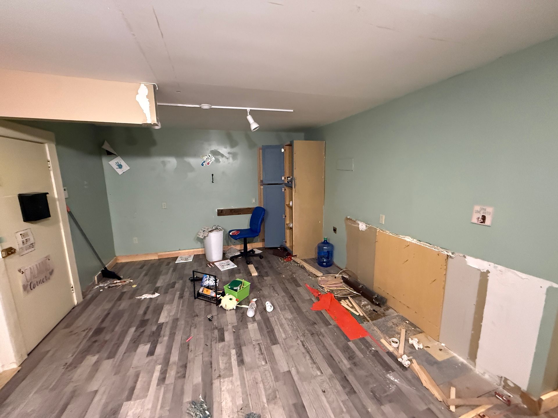 Partially renovated room with gray floors, pale green walls, tools