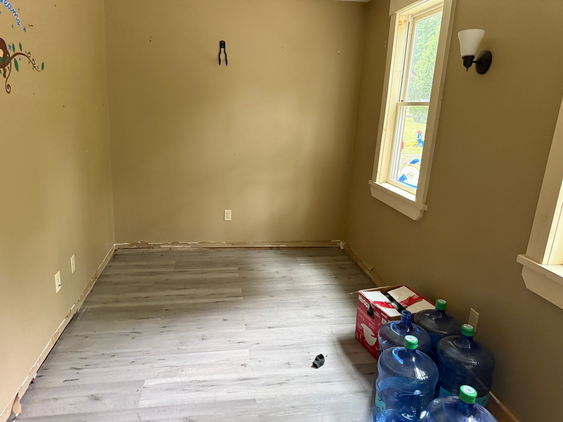 Empty beige room with wood-look flooring, windows