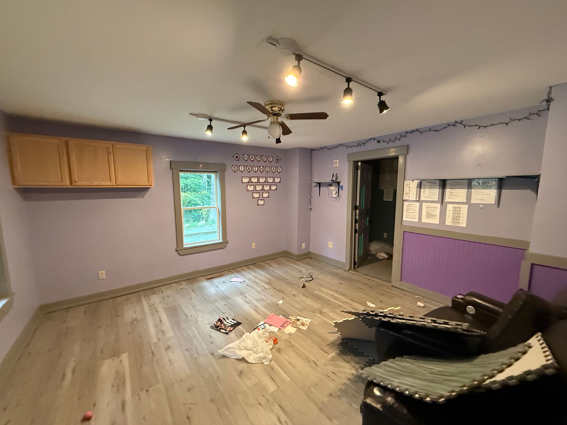 Empty room with lavender walls, wood floor, ceiling fan, window