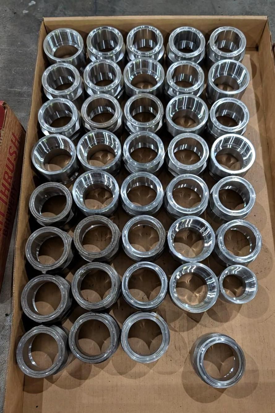 Tray of shiny metal socket heads arranged in rows inside a cardboard box