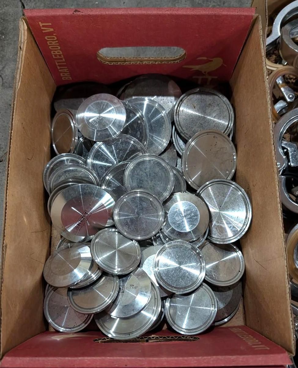 Open cardboard box filled with shiny silver metal discs and washers