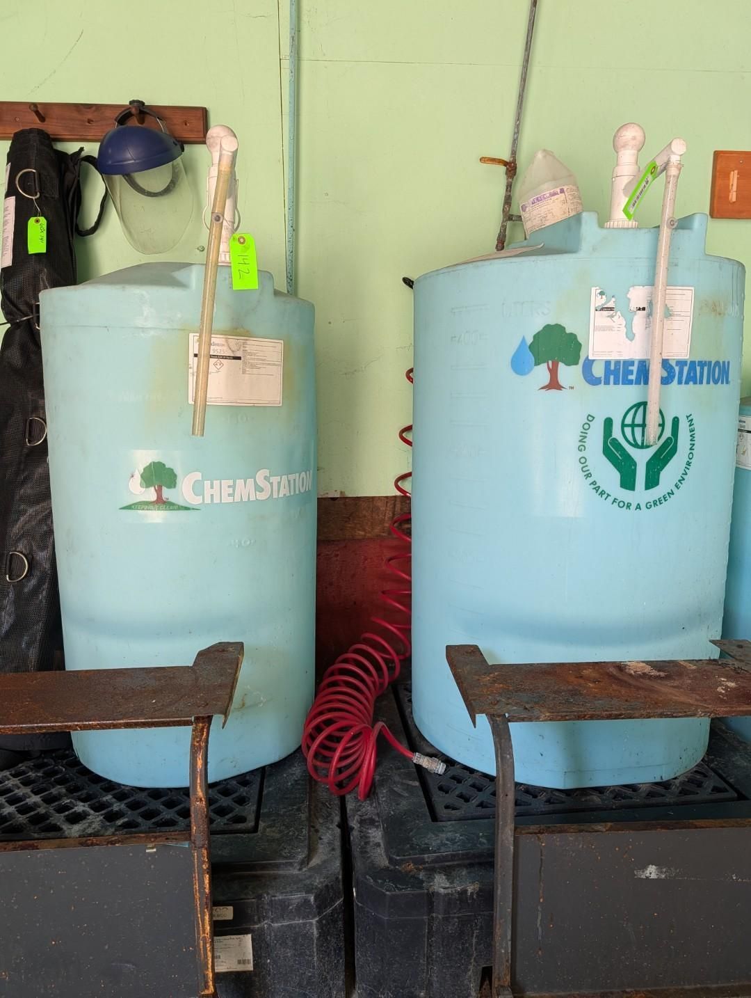 Two light-blue tanks with hoses and regulators in a workshop corner