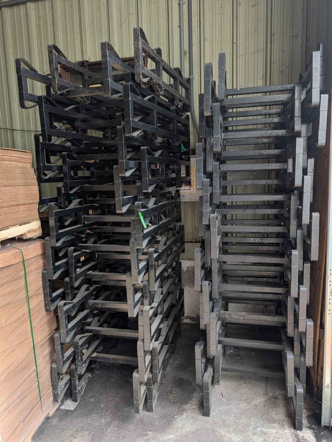 Stacked black metal racks in a warehouse aisle, with tall shelves lined along both sides.