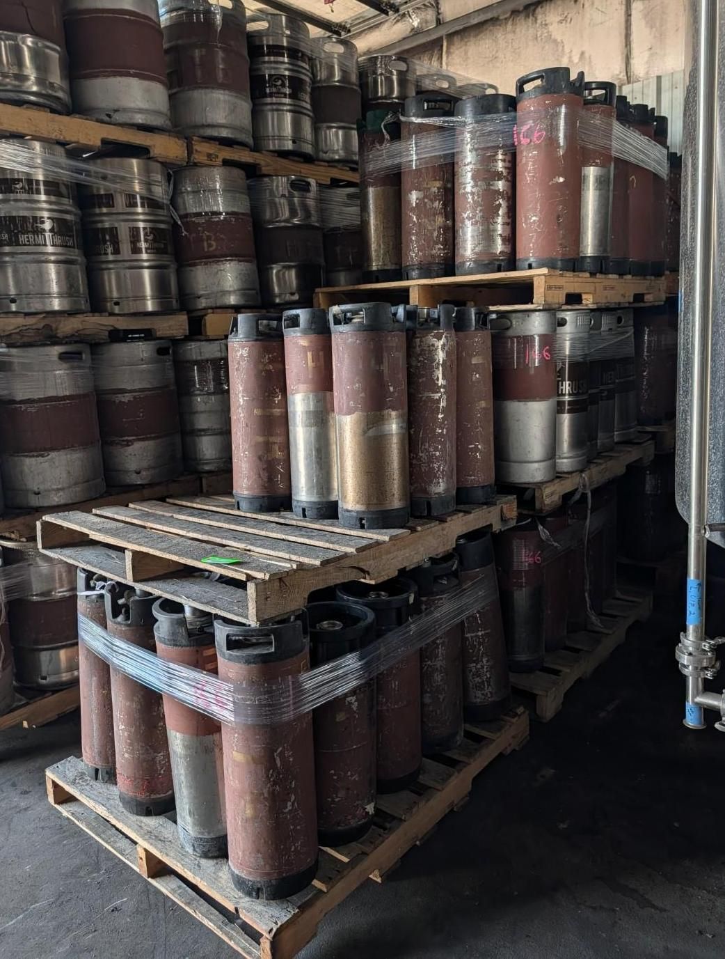Stacked metal cylinders on pallets in a warehouse storage area.