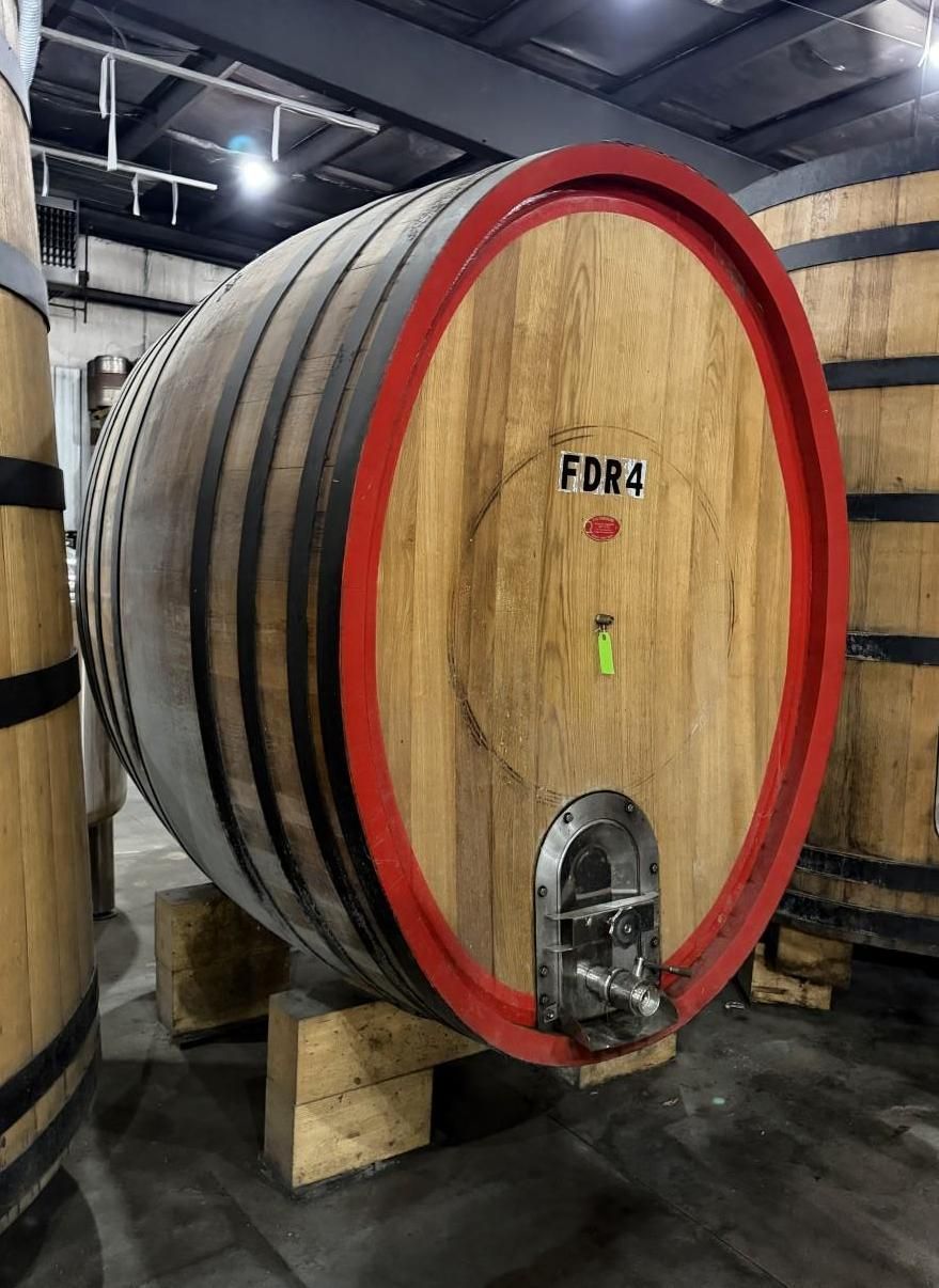 Large wooden wine barrel with red rim in an industrial cellar