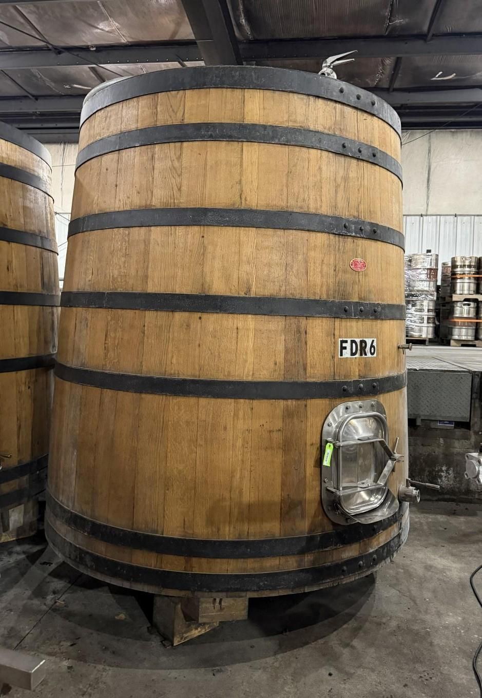 Large wooden barrel tank with metal bands in an industrial warehouse