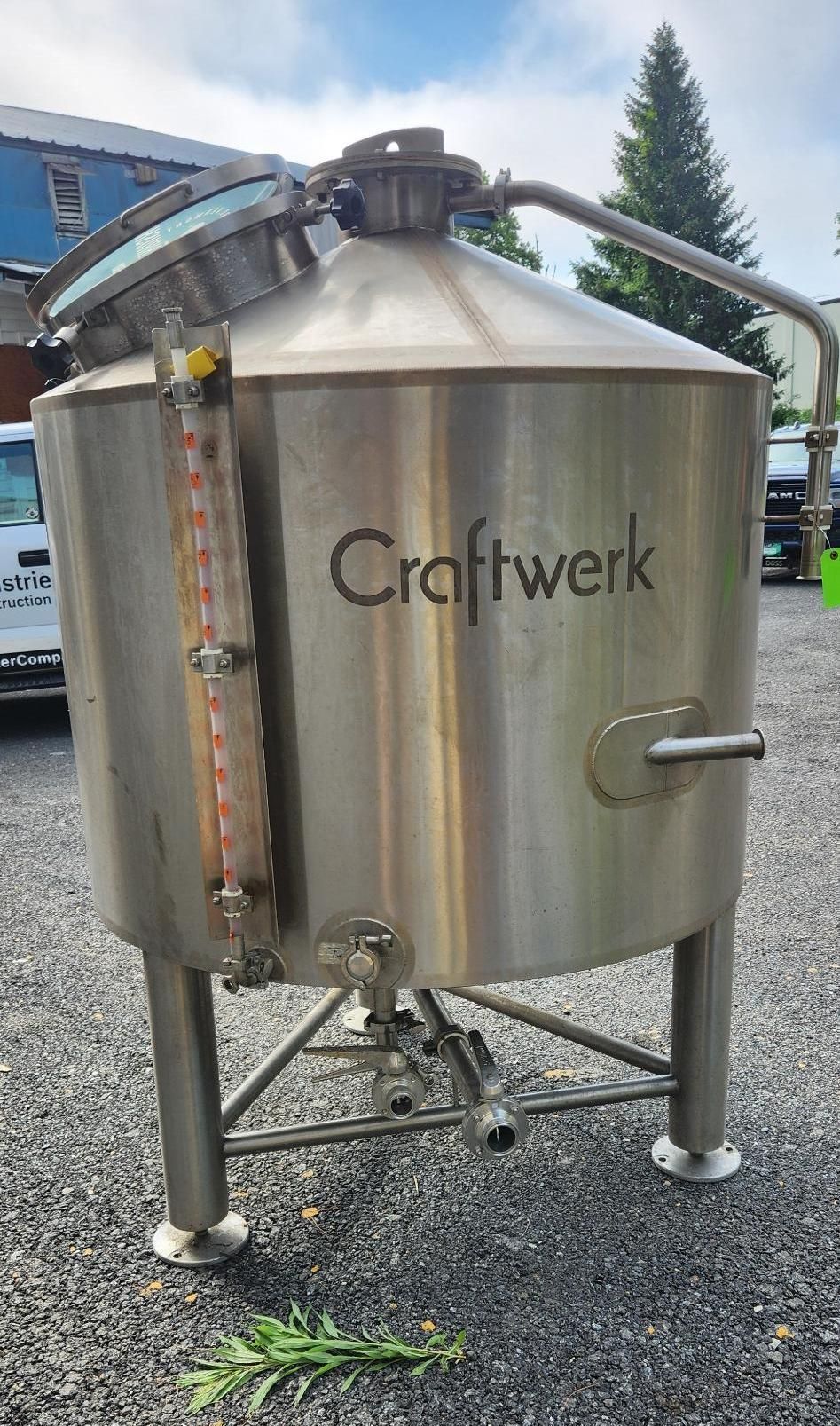 Stainless steel Craftwerk brewing tank with domed top and side gauge outdoors on gravel