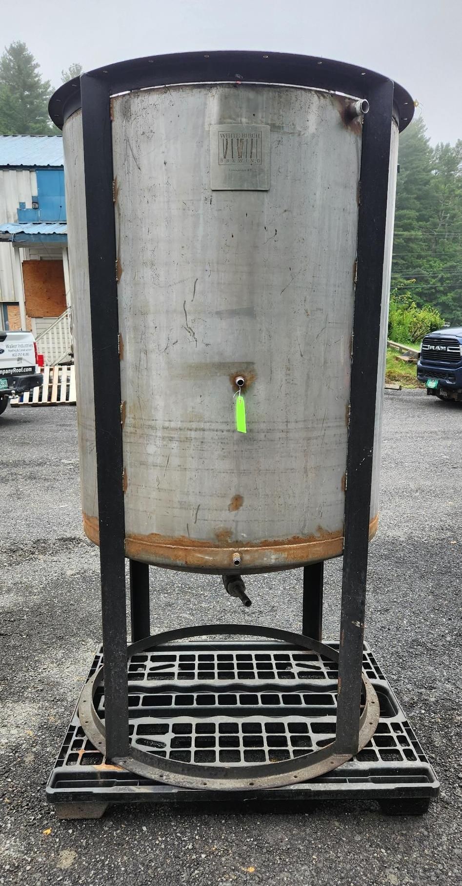 Large cylindrical metal tank on a black frame over a grated base outdoors, with a small green valve.