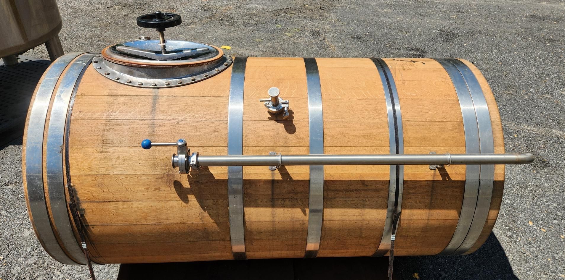 Wooden barrel-style tank with metal bands and a side thermometer, outdoors