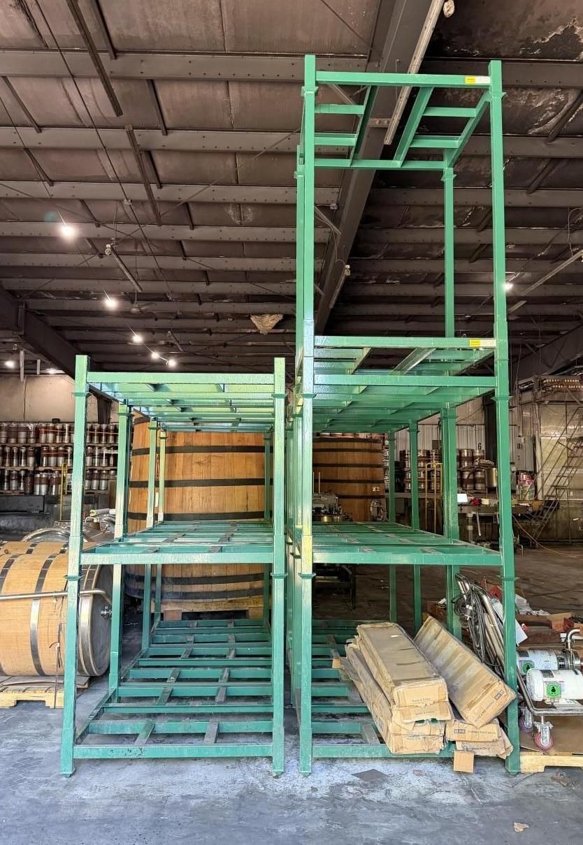 Mint-green metal storage racks in a warehouse, with stacked lumber and boards on the floor.