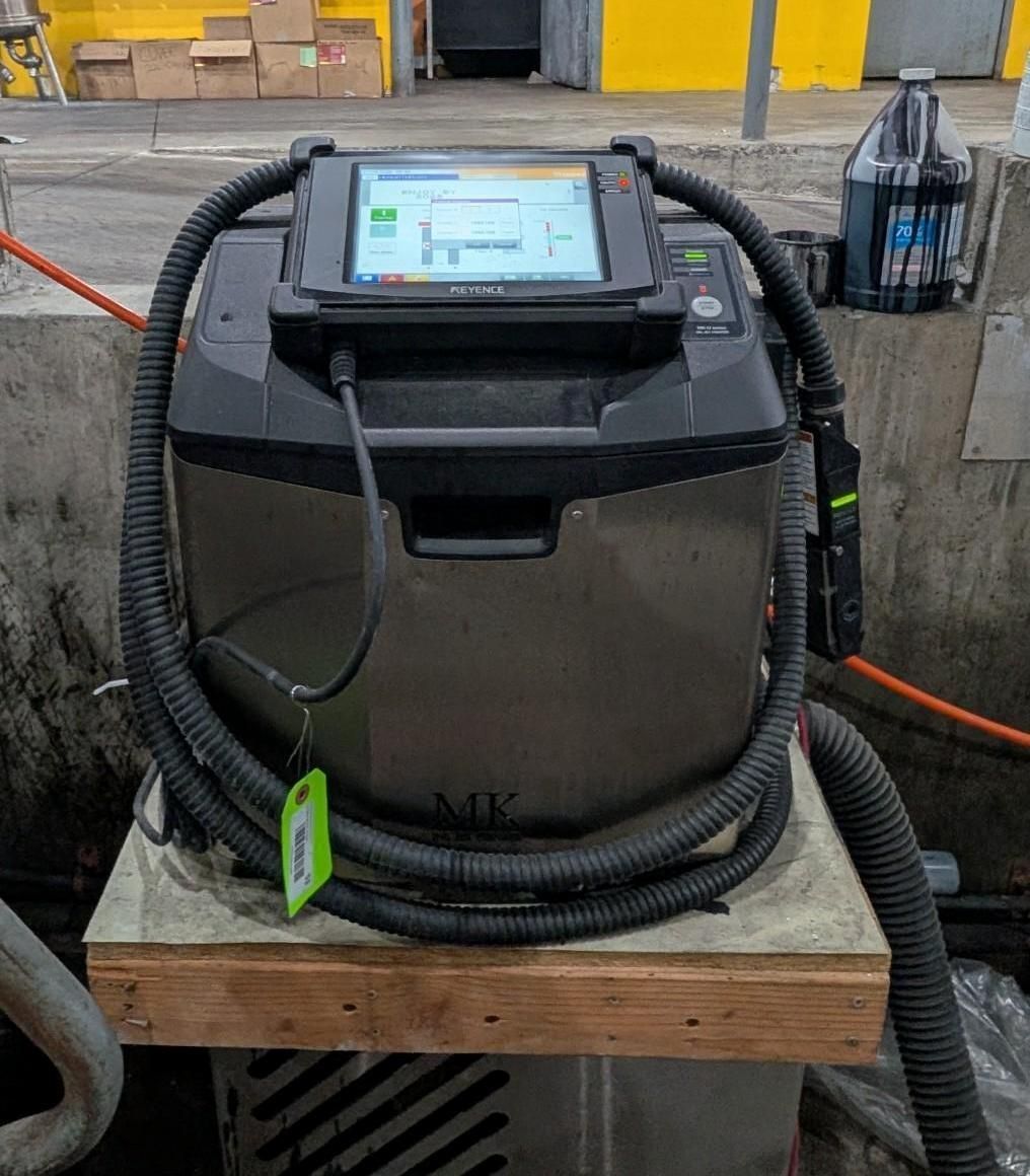 Black industrial device with screen and coiled hose on a wooden pallet in a workshop