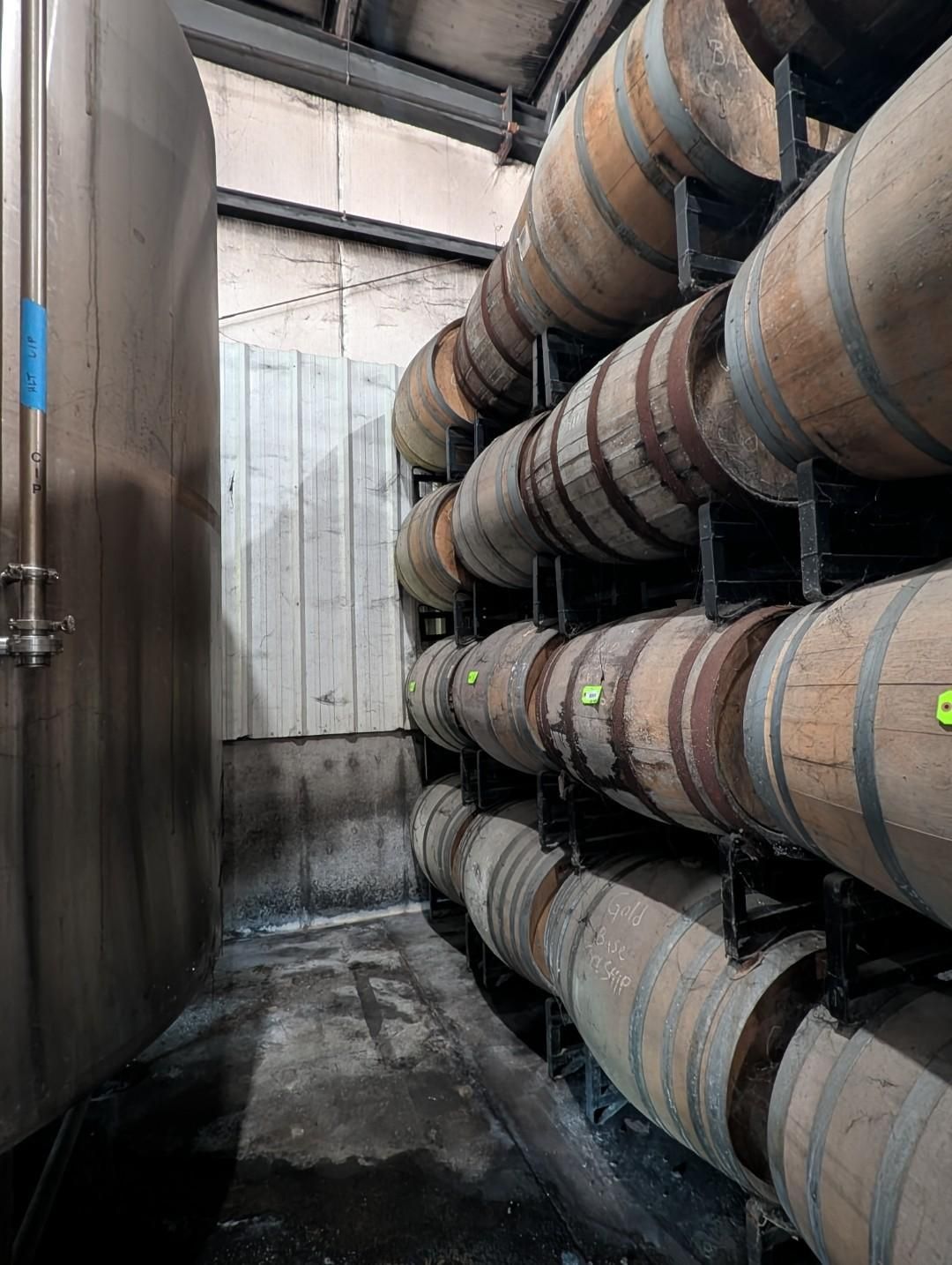 Industrial corridor with large stacked barrels beside a metal tank in a storage area