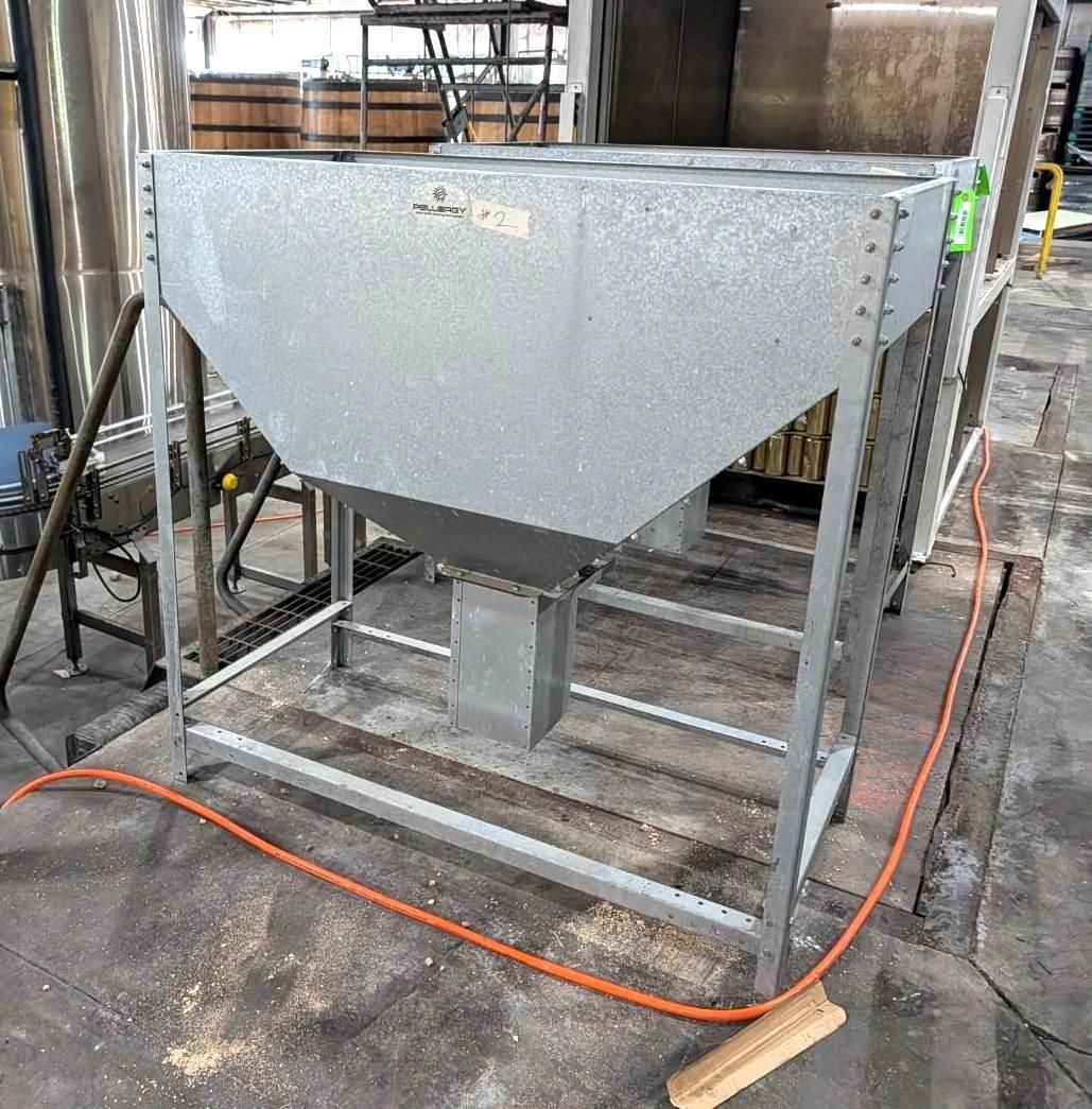 Large gray industrial metal hopper on a wheeled frame in a workshop