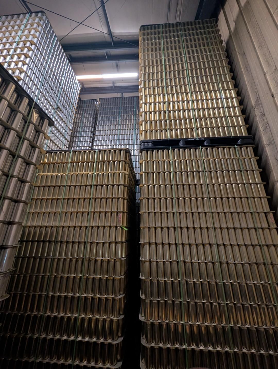 Stacks of metal cans piled high inside a warehouse corridor.