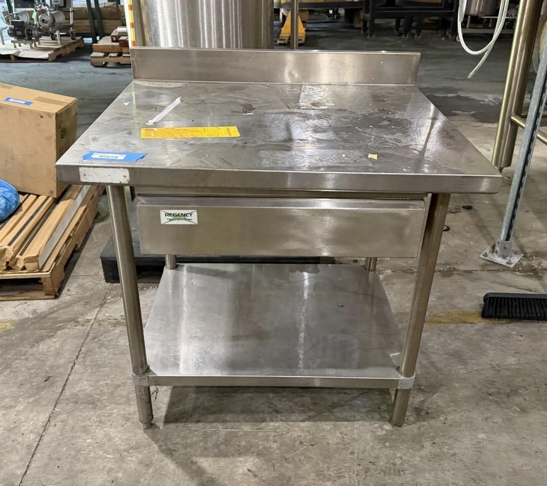 Stainless steel work table with lower shelf in an industrial kitchen or workshop setting