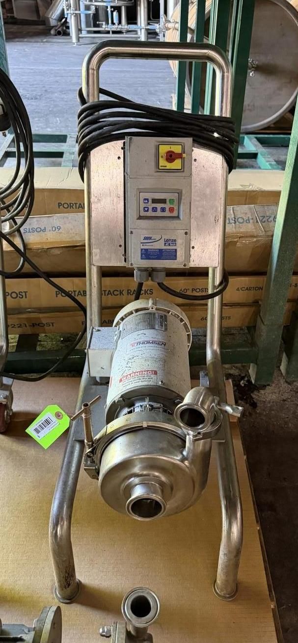 Industrial pump/motor unit on a metal frame with attached control box and cables in a workshop setting