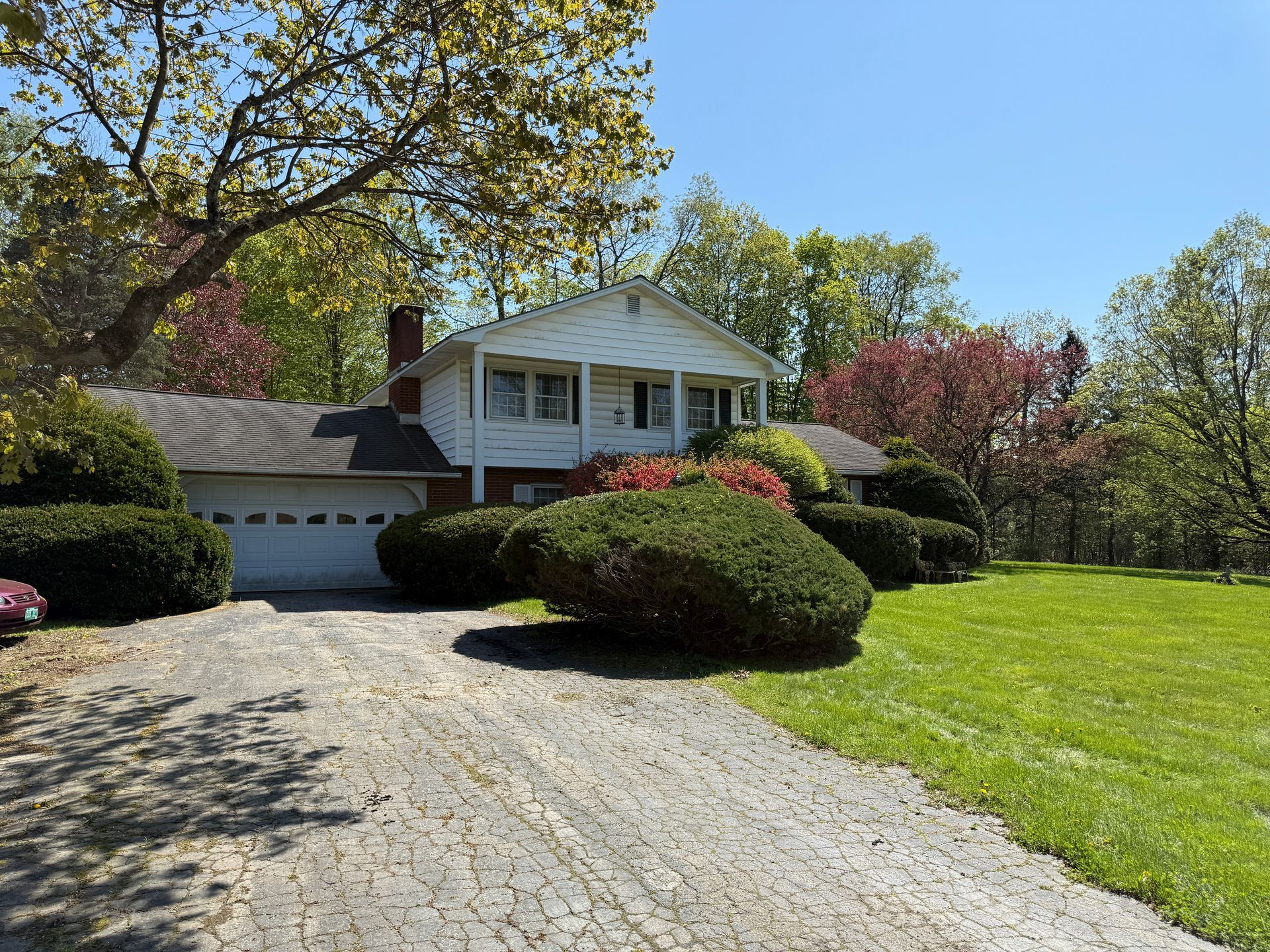 A two-story white house with a driveway and green lawn on a sunny day.