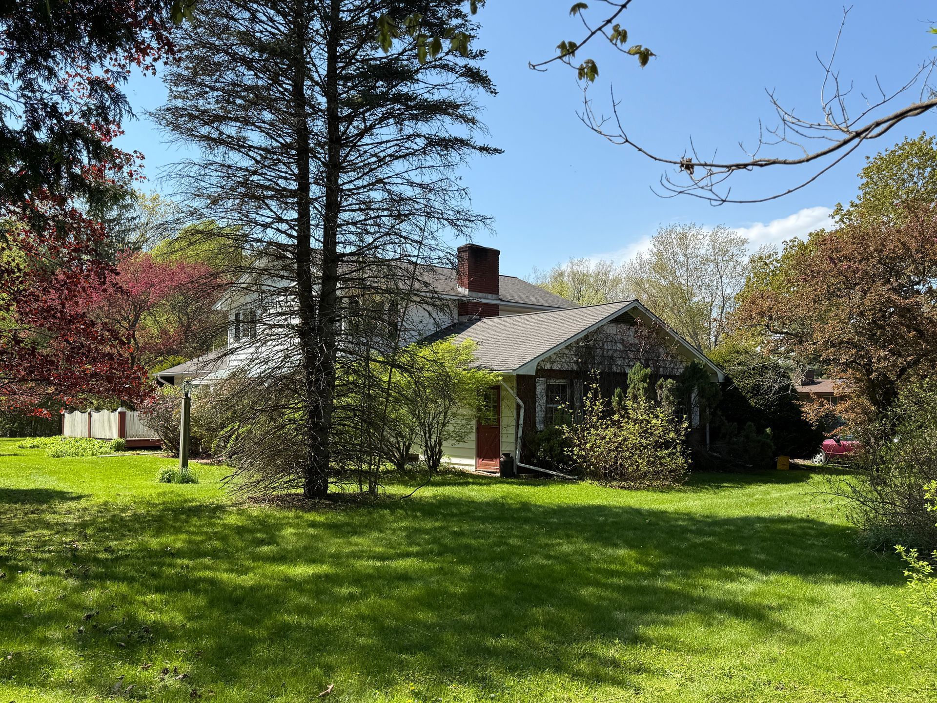 White house with green lawn, trees, and blue sky.