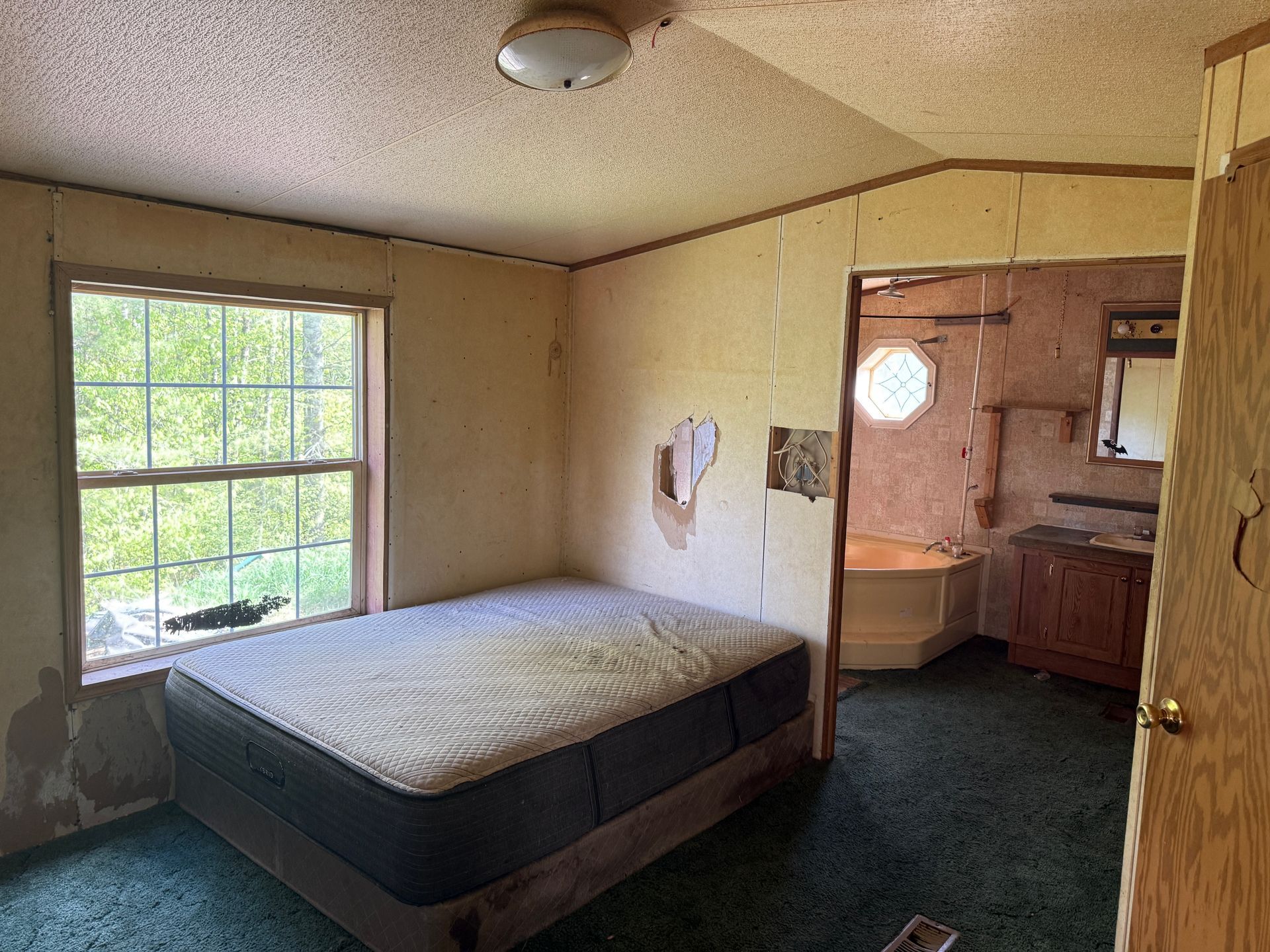 Bedroom with bed, window, and doorway to bathroom.