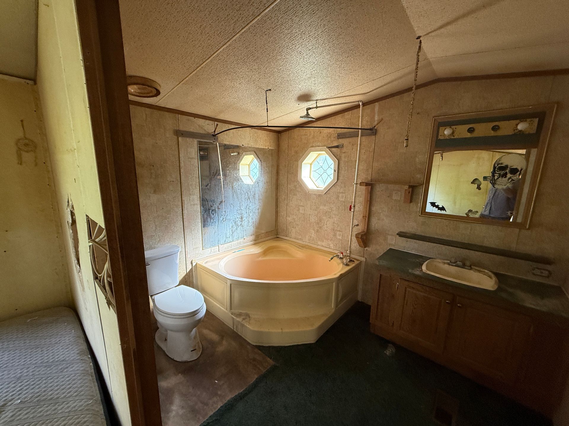 Bathroom interior with a bathtub, toilet, vanity, and round window. Beige and brown tones.