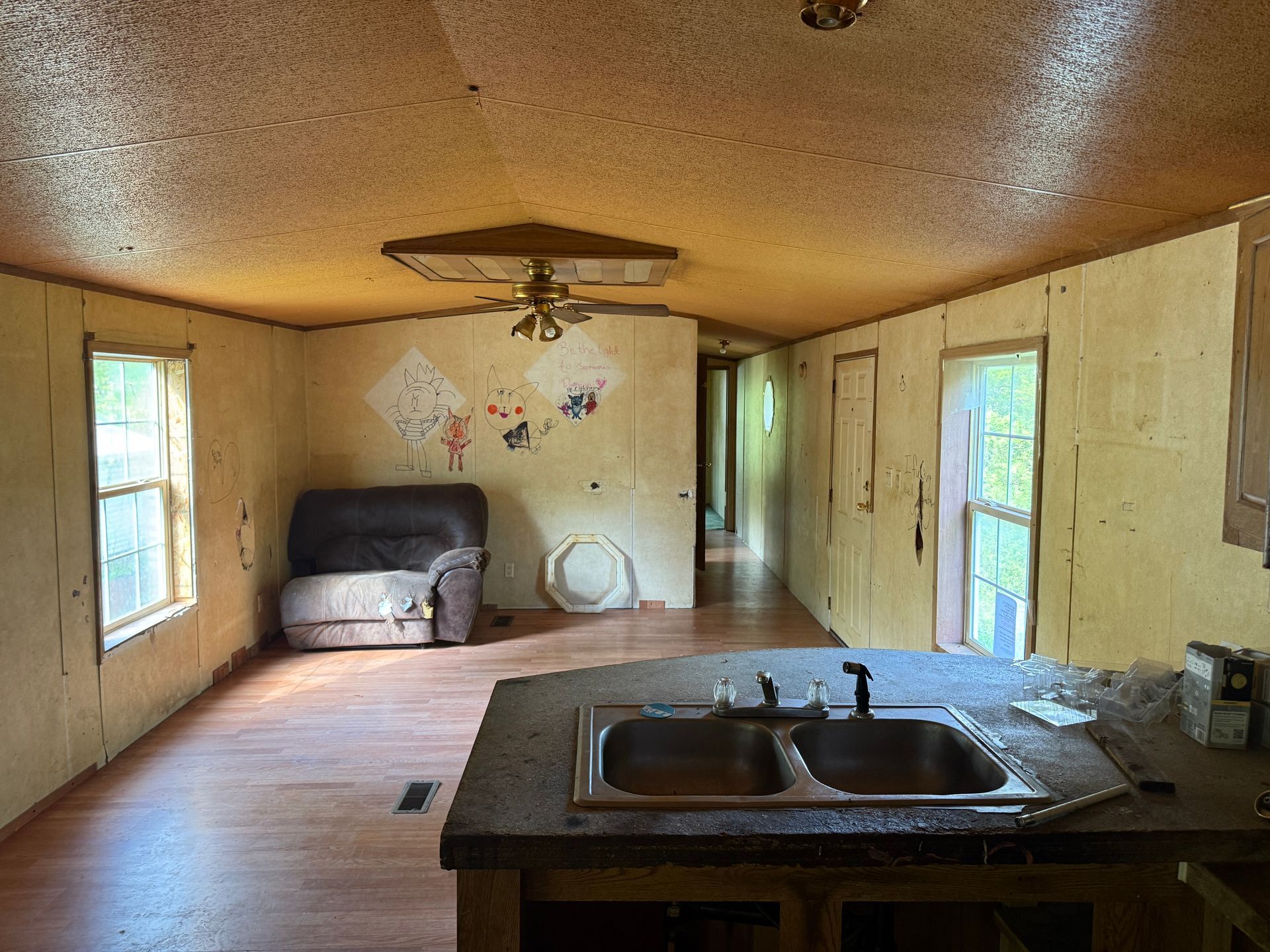 Interior of a mobile home with a kitchen sink, living area with a couch, and hallway.