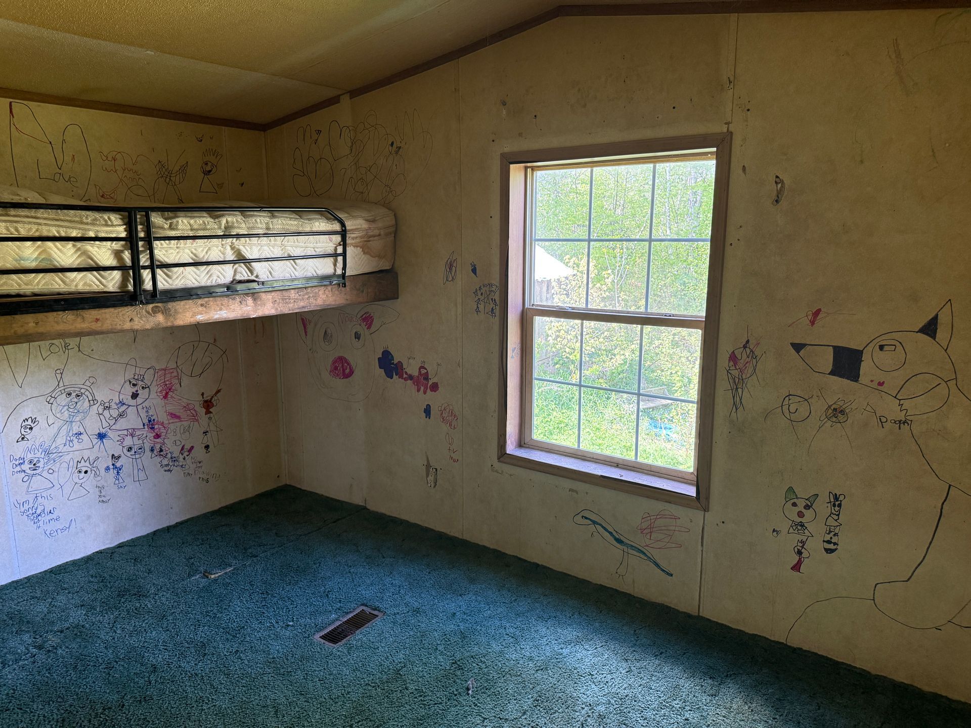 A small room with a bunk bed, window, green carpet.
