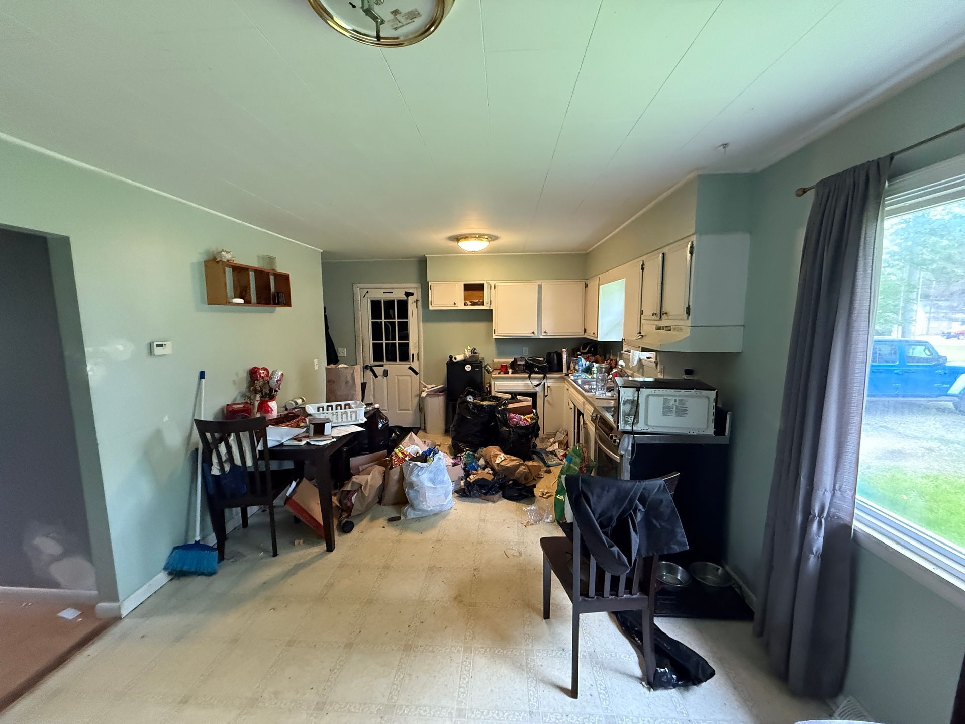 Kitchen with counters, and a partially visible window with curtains.