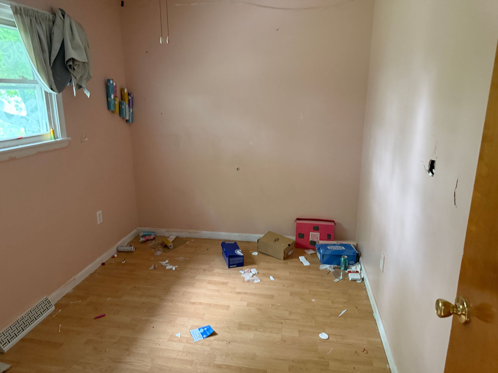 Room with pink walls, wooden floor, window.