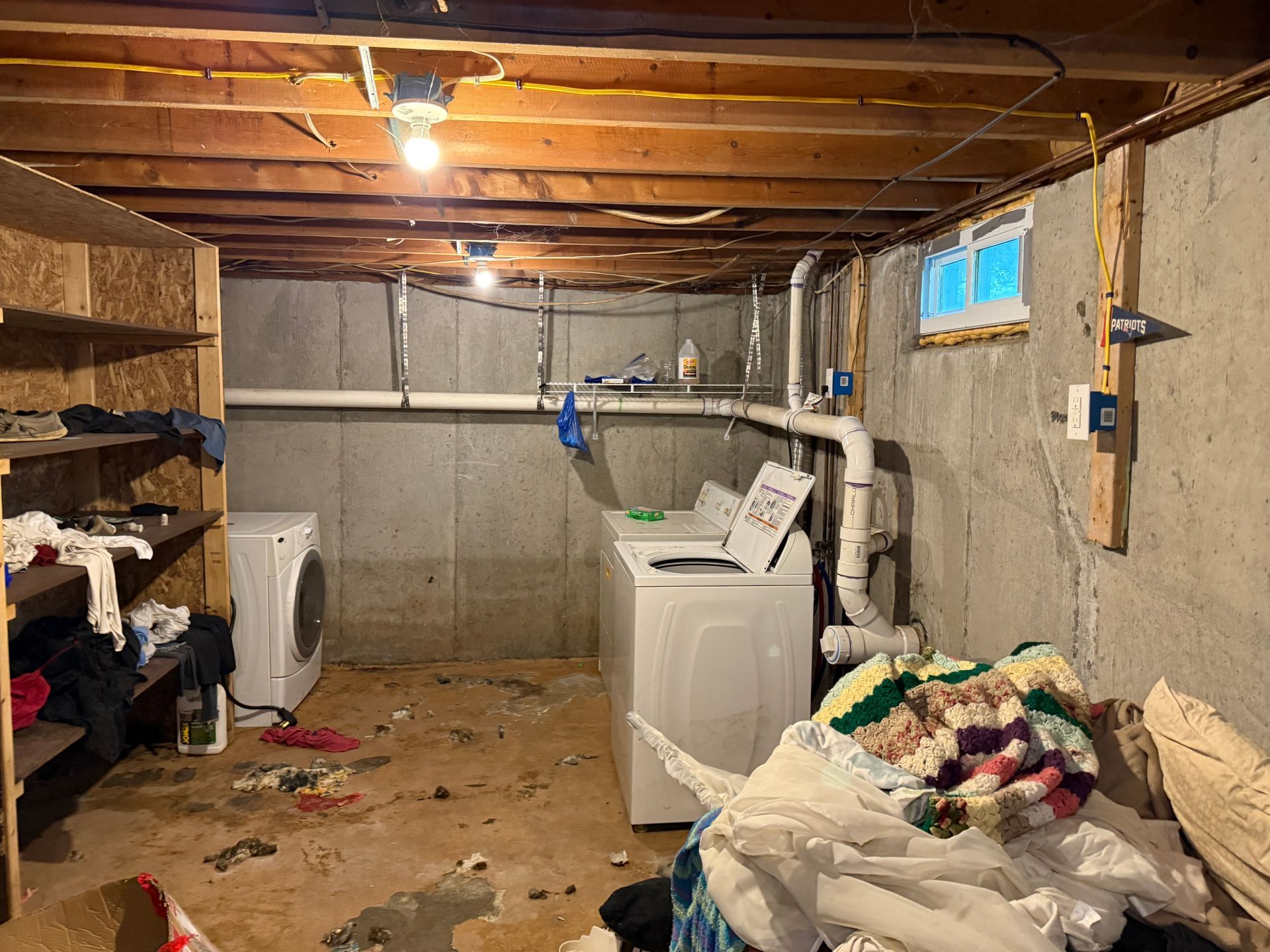 Basement laundry room with washing machines, exposed pipes.