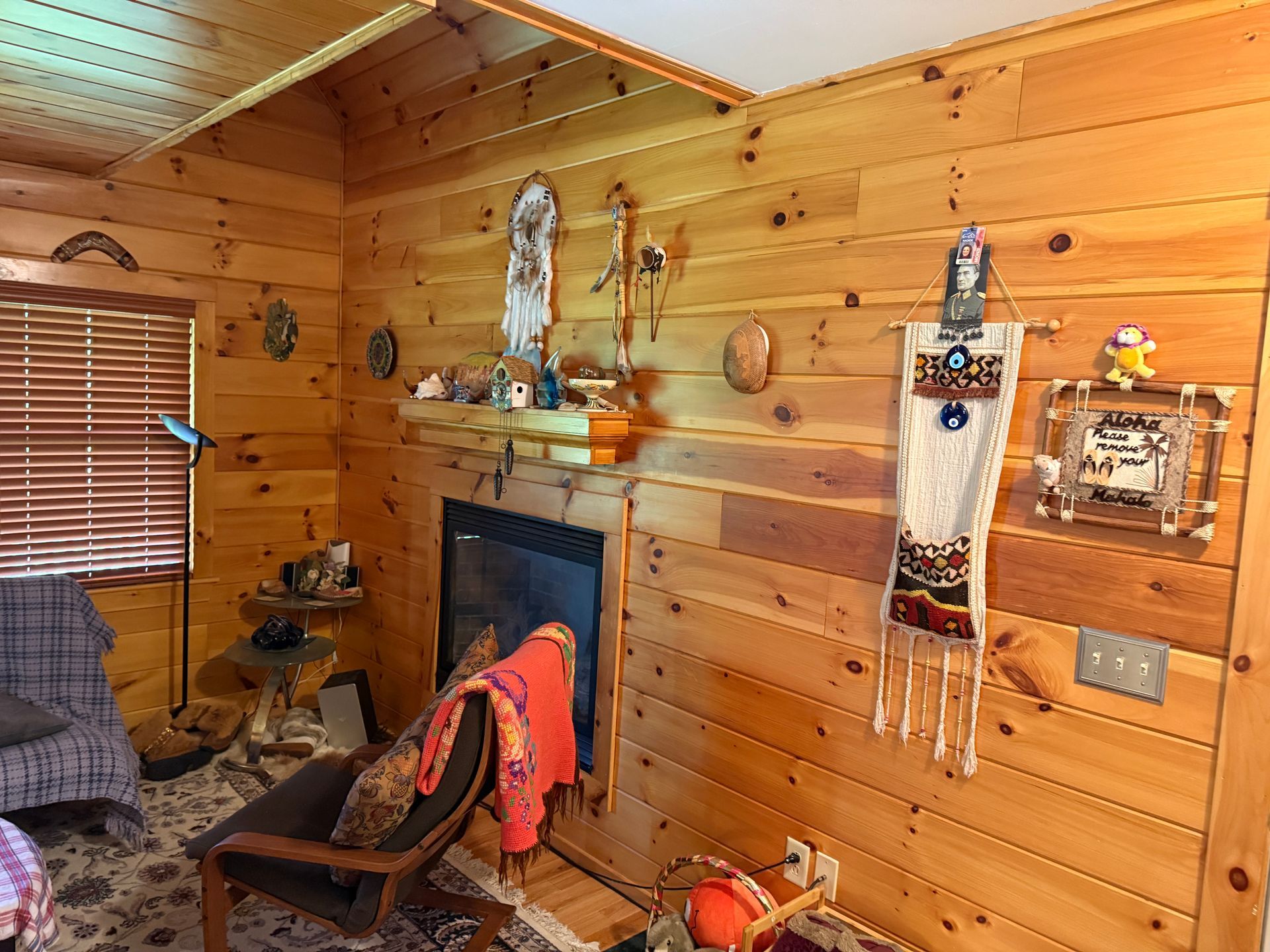 Cozy living room with wood-paneled walls, fireplace, and various decorations.