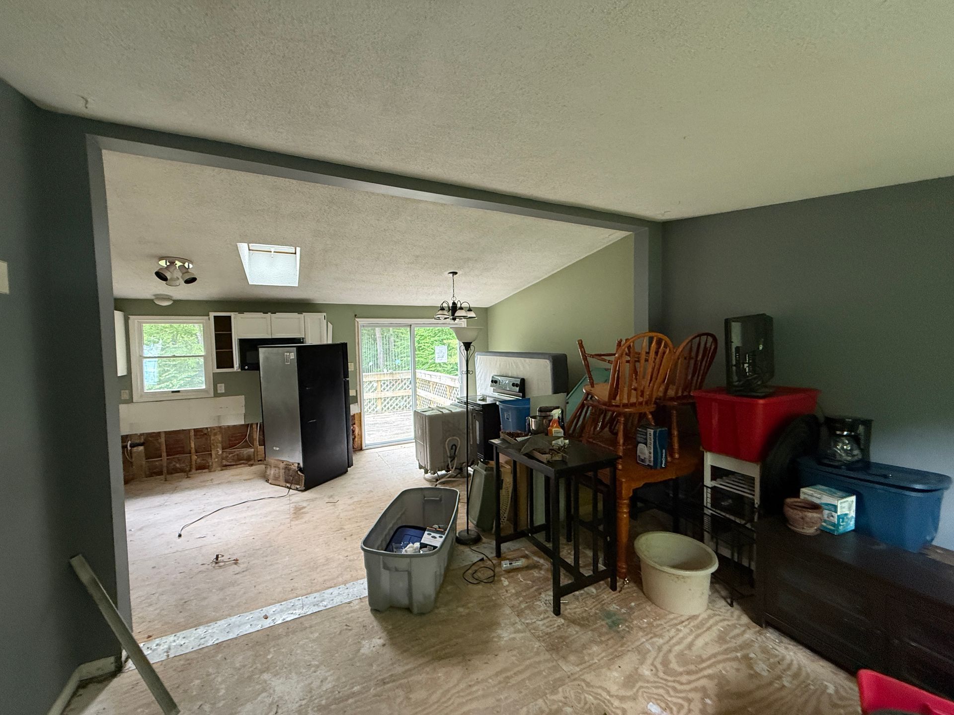 Interior of a house: kitchen and living room, gray walls, sunlight.