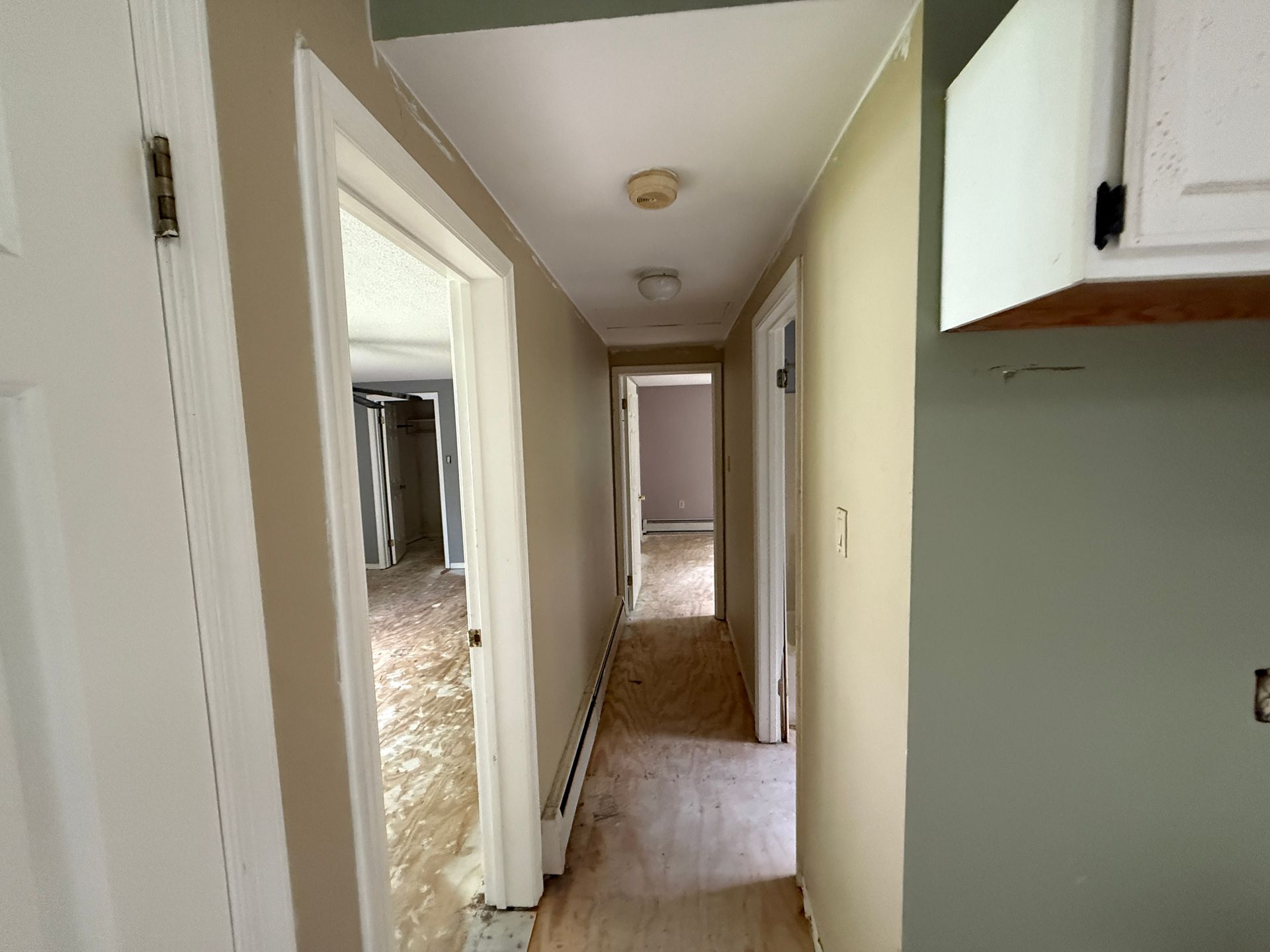 Hallway with doors, and partial kitchen.