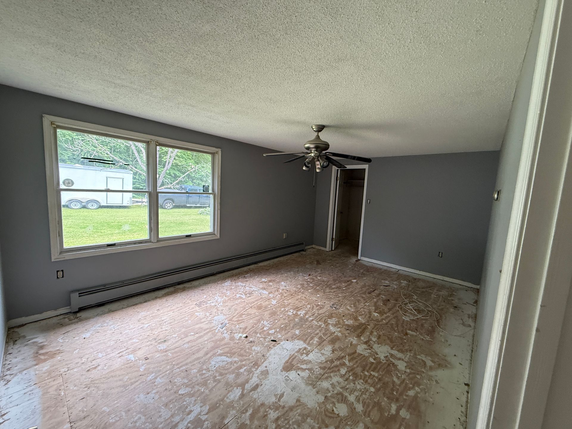 Empty room with gray walls, window, ceiling fan.