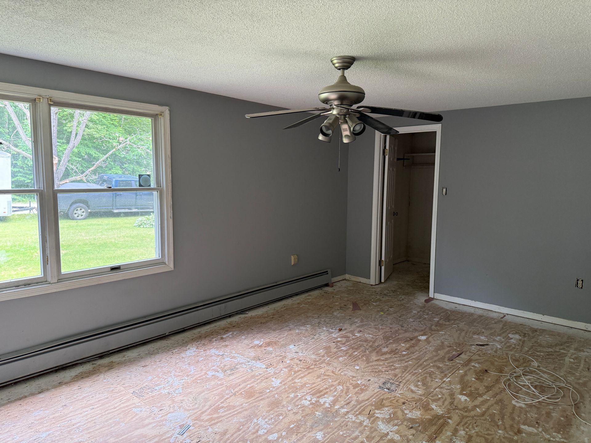 Empty room with gray walls, window, ceiling fan.