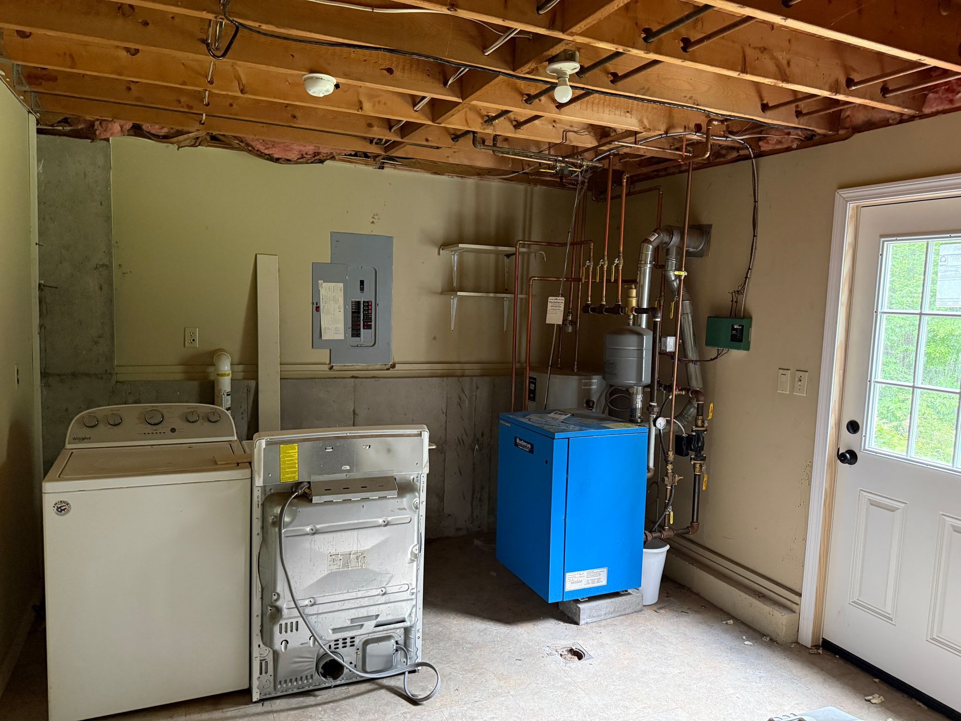 Laundry room with washer, dryer, electrical panel, blue furnace, and back door.