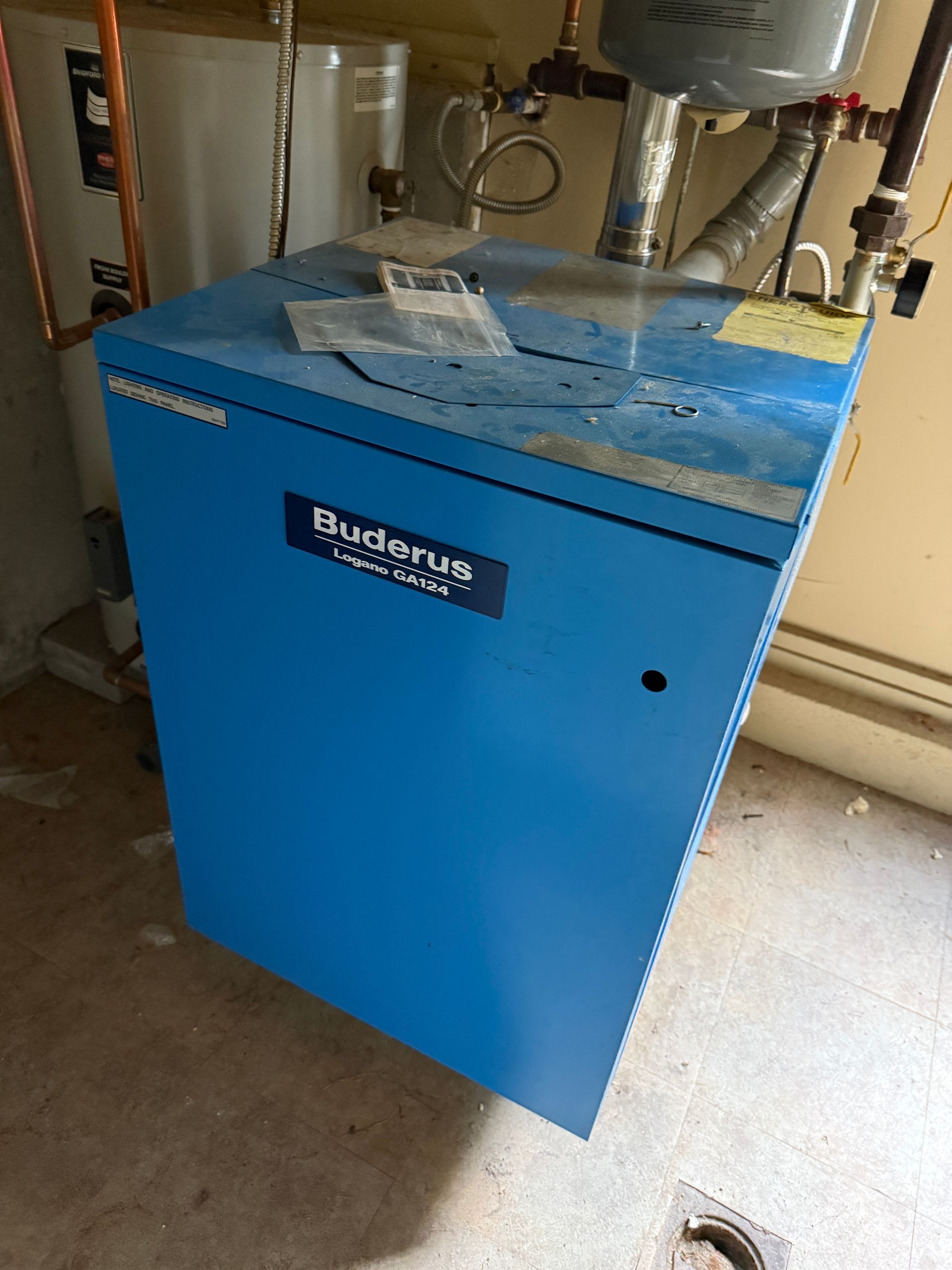 Blue Buderus boiler in a utility room, next to a water heater and pipes.