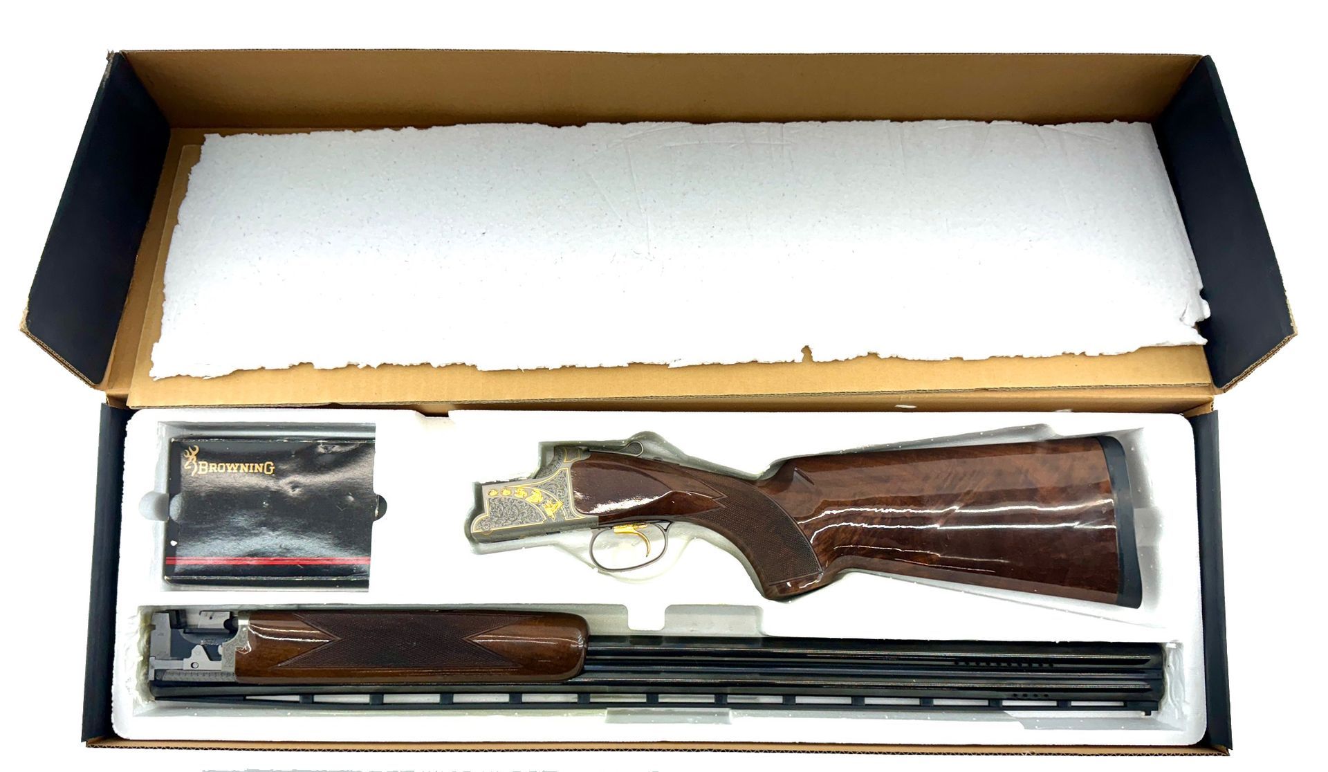 Shotgun in a box, disassembled, with wooden stock, black barrel, and silver receiver.