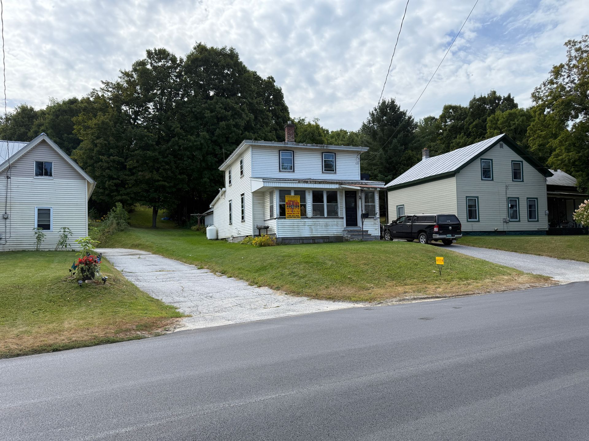 White House sits along a road with green lawns and gravel driveways. Overcast sky.