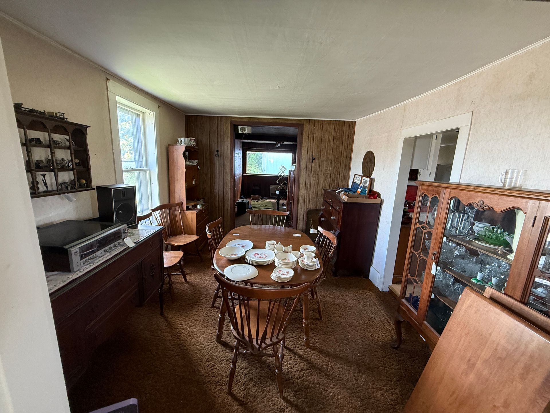 A dining room with an oval table, china, and antique furniture.