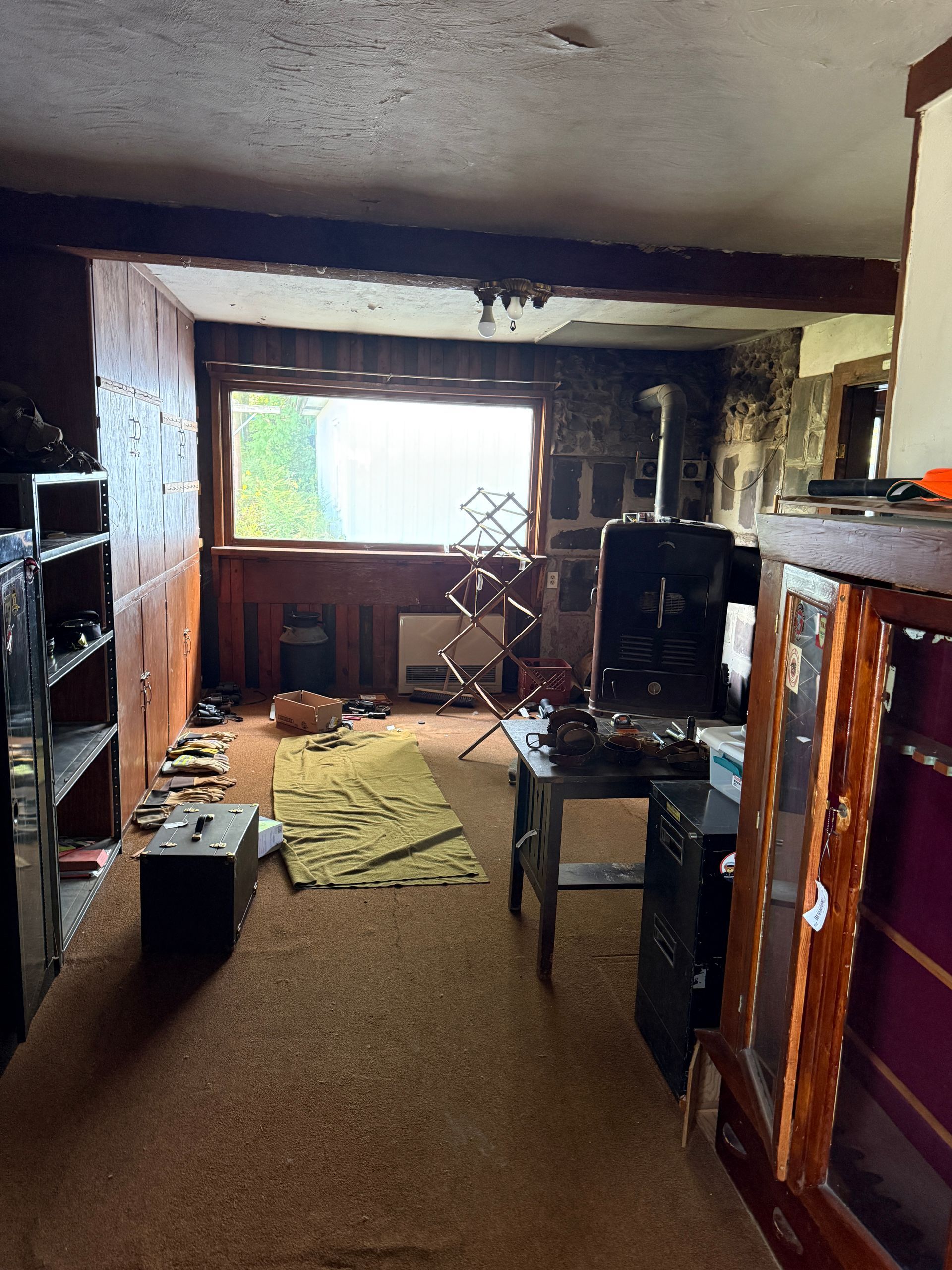 Interior of a room with a window, shelves, and various objects.